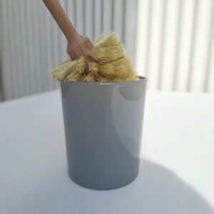 Portaescobillas de WC Waldkraft de vidrio gris y negro junto a escobillas de madera.